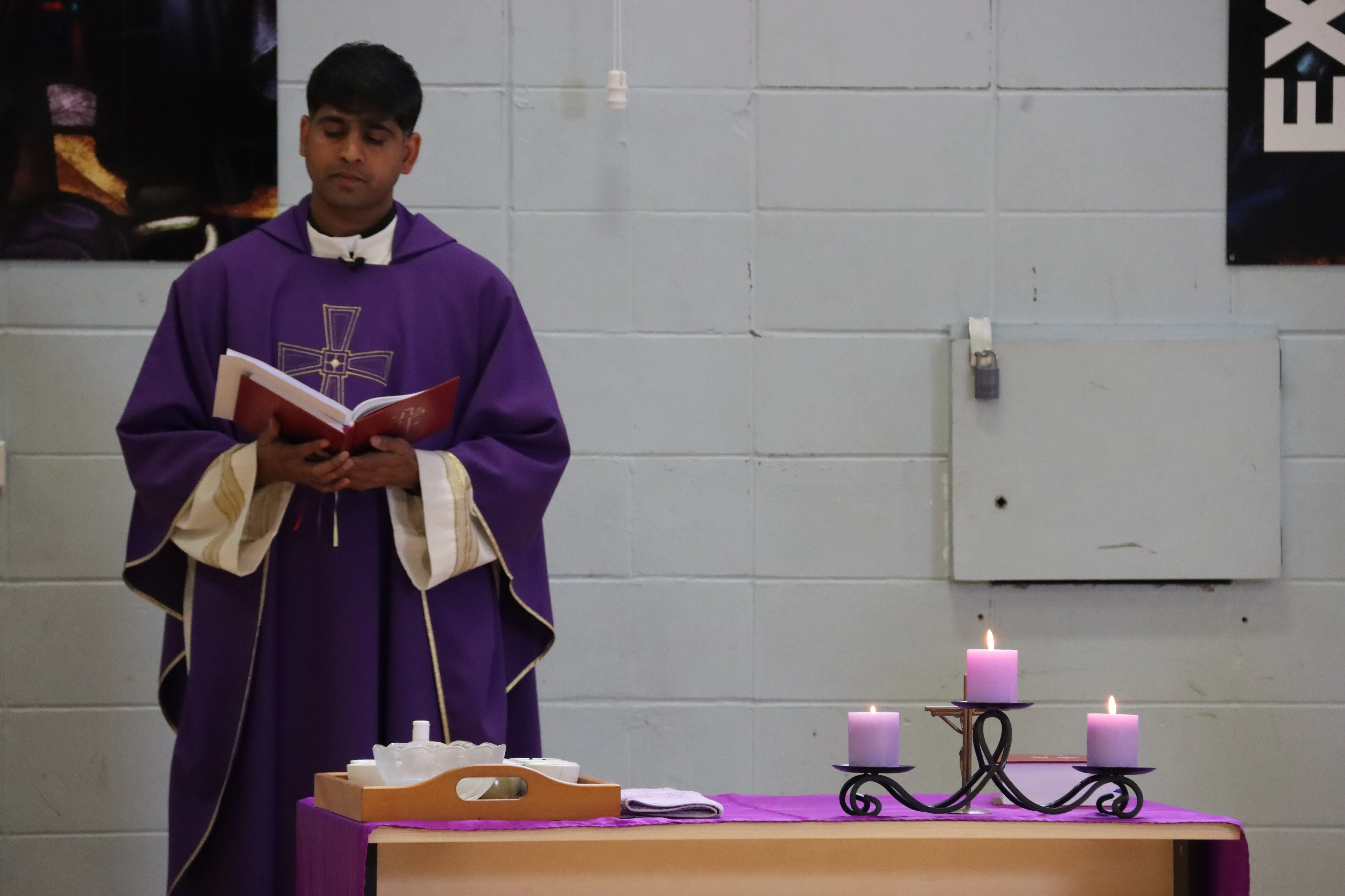 Image of Father Prakesh reading from the Bible