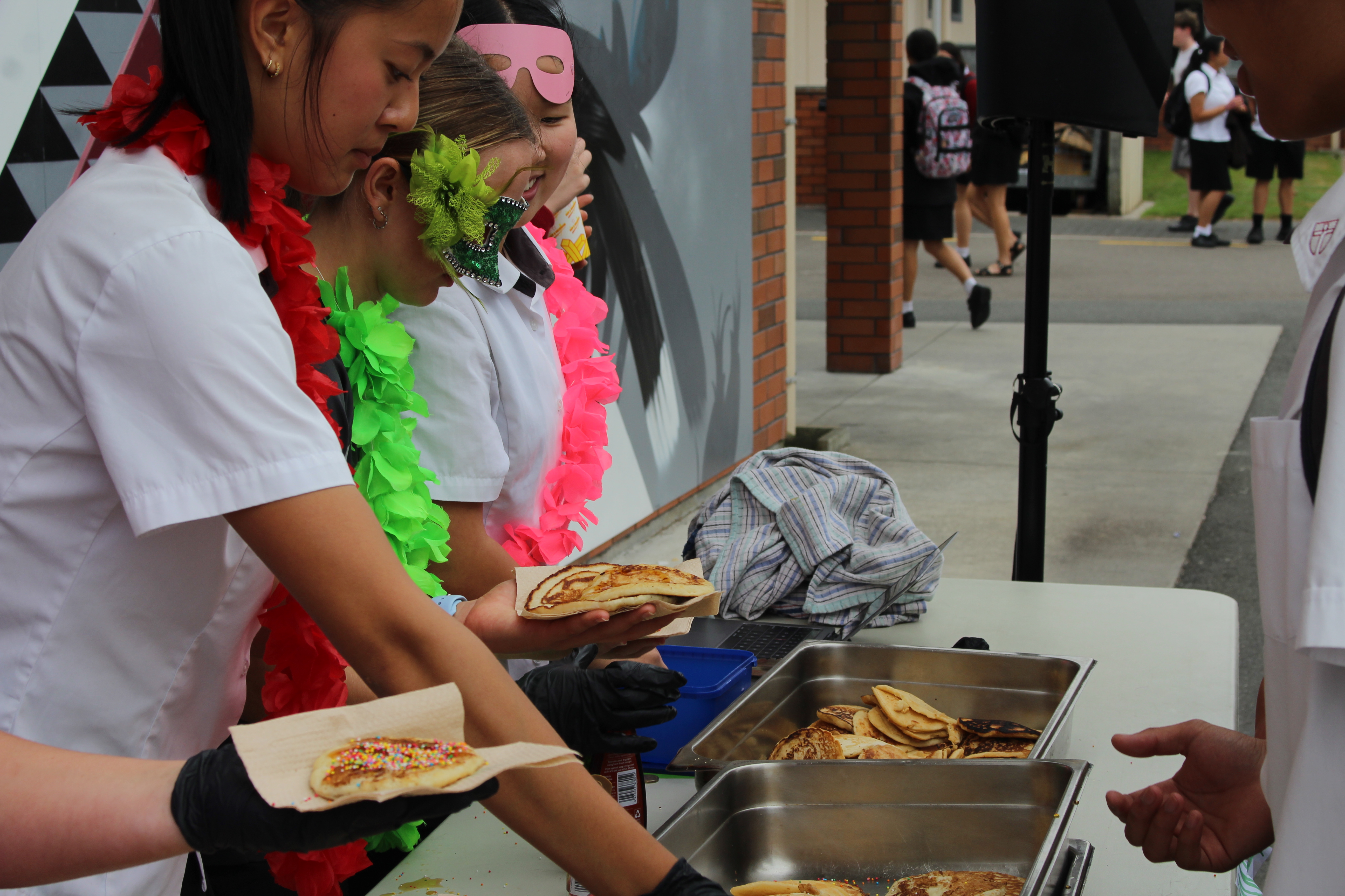 Image of people serving pancakes at the Mardi Gras event